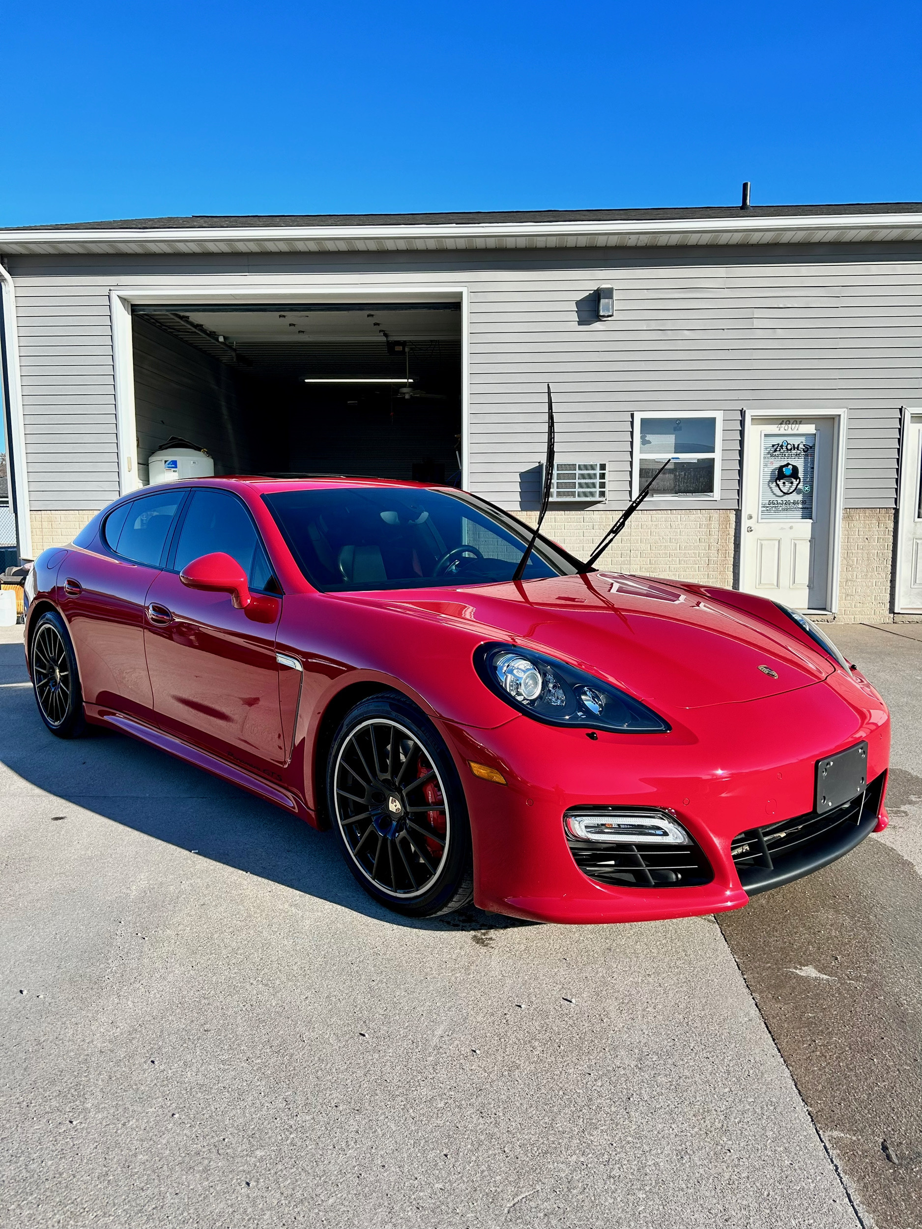 Red Porsche Panamera with butterfly doors at Zach's Master Detailing shop
